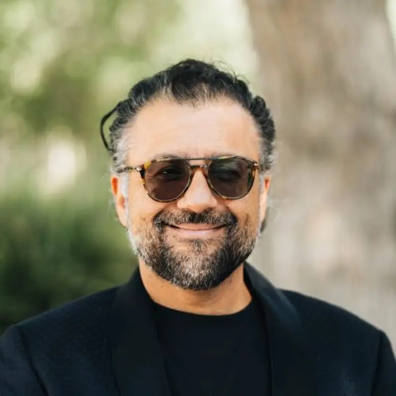 Dr. Varun Soni, Coacharya board member, smiling in sunglasses and a dark jacket outdoors