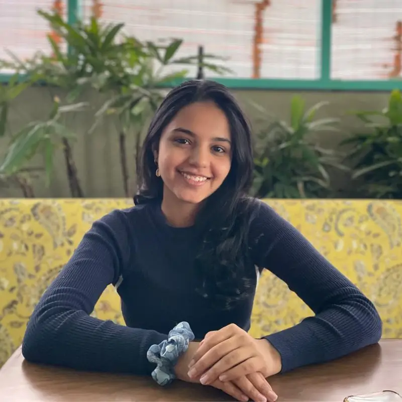 Aakanksha Buch, Youth Initiative Lead at Coacharya Foundation, seated at a table with plants behind her
