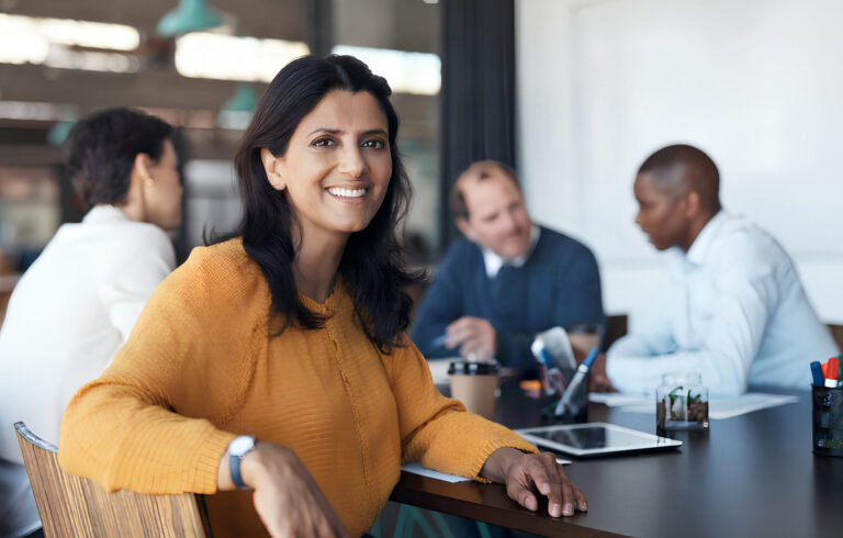 Manager leading a discussion with two colleagues around a meeting room table